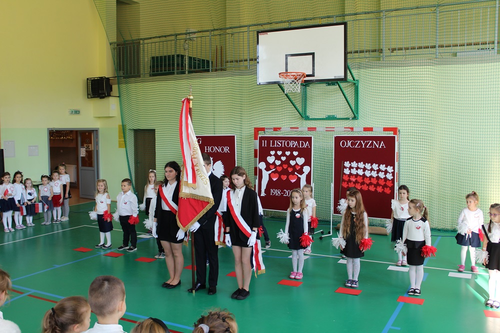 zdjęcie przedstawia uczniów występujących na akademii z okazji Święta 11 listopada wraz z pocztem sztandarowym szkoły