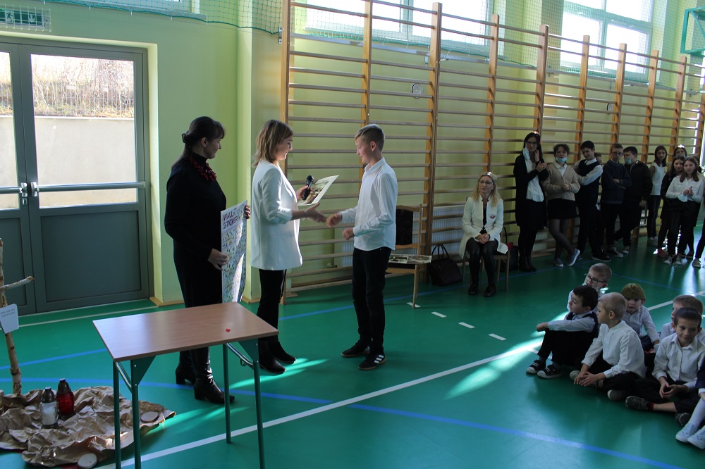 zdjęcie przedstawia ucznia odbierającego nagrodę za udział w konkursie ortograficznym