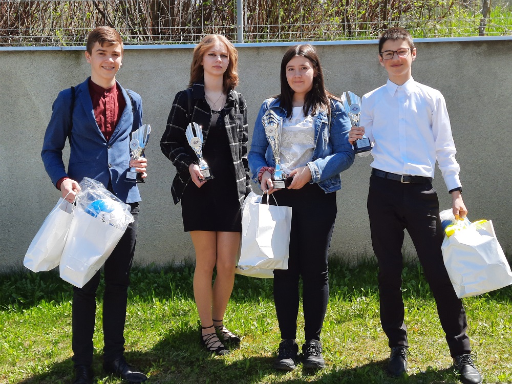 zdjęcie przedstawia 4 uczniów wraz z odebranymi nagrodami