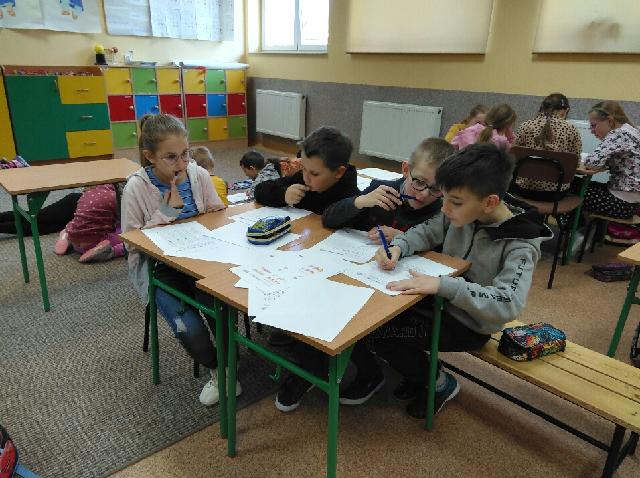 zdjęcie przedstawia grupę uczniów rozwiązujących zadania matematyczne
