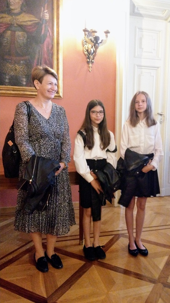 dwie dziewczynki z nauczycielką podczas wręczania dyplomów i nagród w Pałacu Biskupim w Krakowie