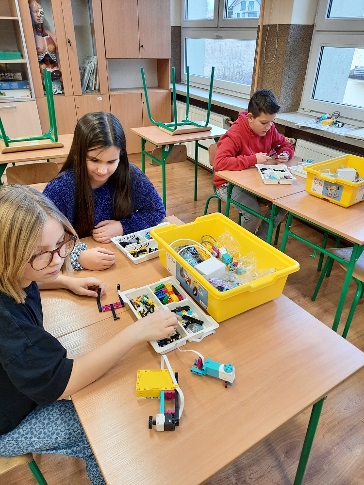 troje dzieci budujących robota z klocków Lego SPIKE Prime
