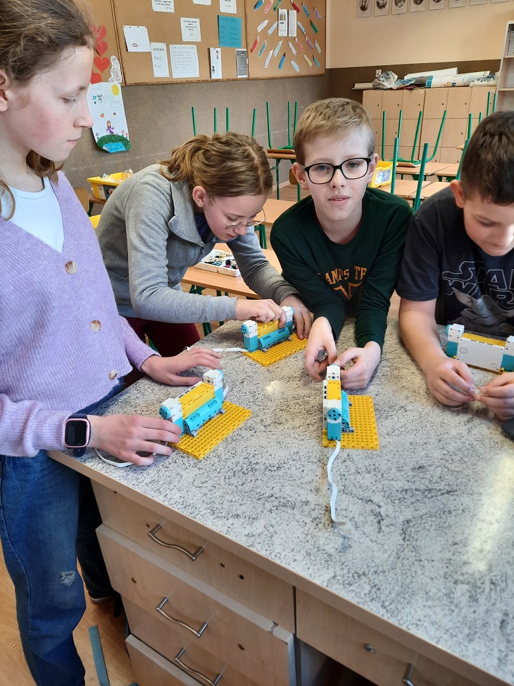 czworo uczniów podczas budowania i testowania maszyny CNC z klocków Lego