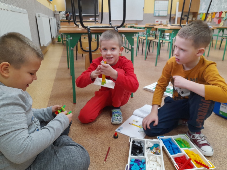 troje uczniów podczas budowania z klocków Lego