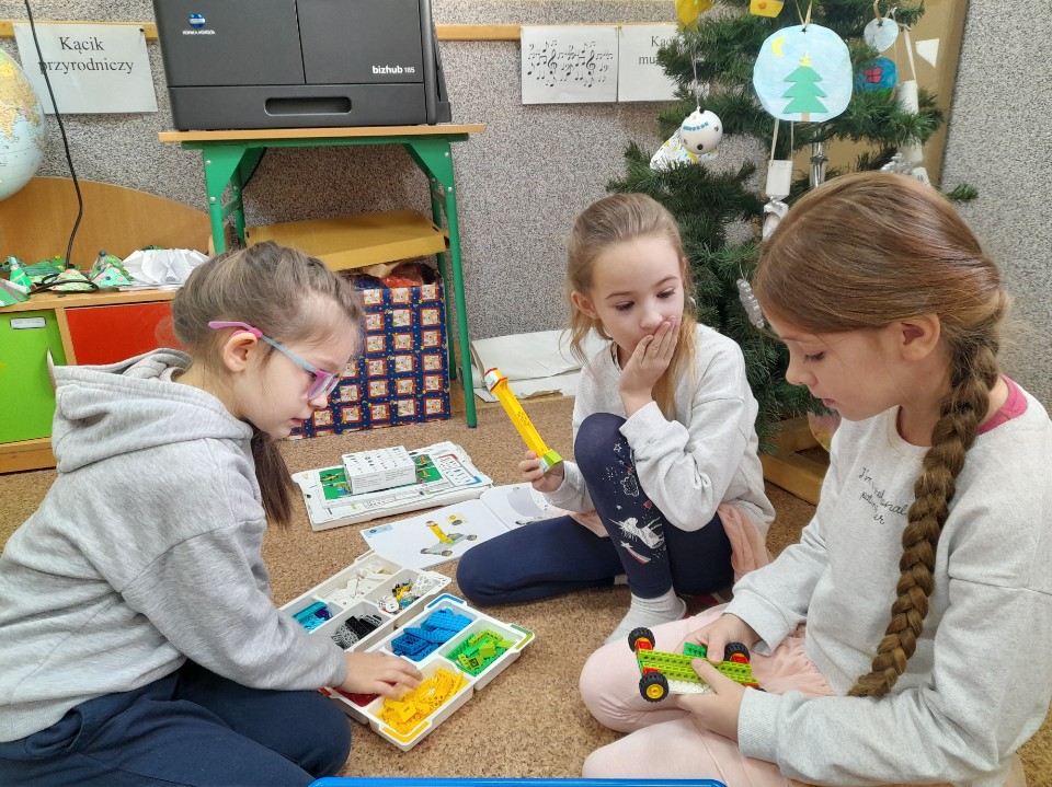 troje uczniów podczas budowania z klocków Lego