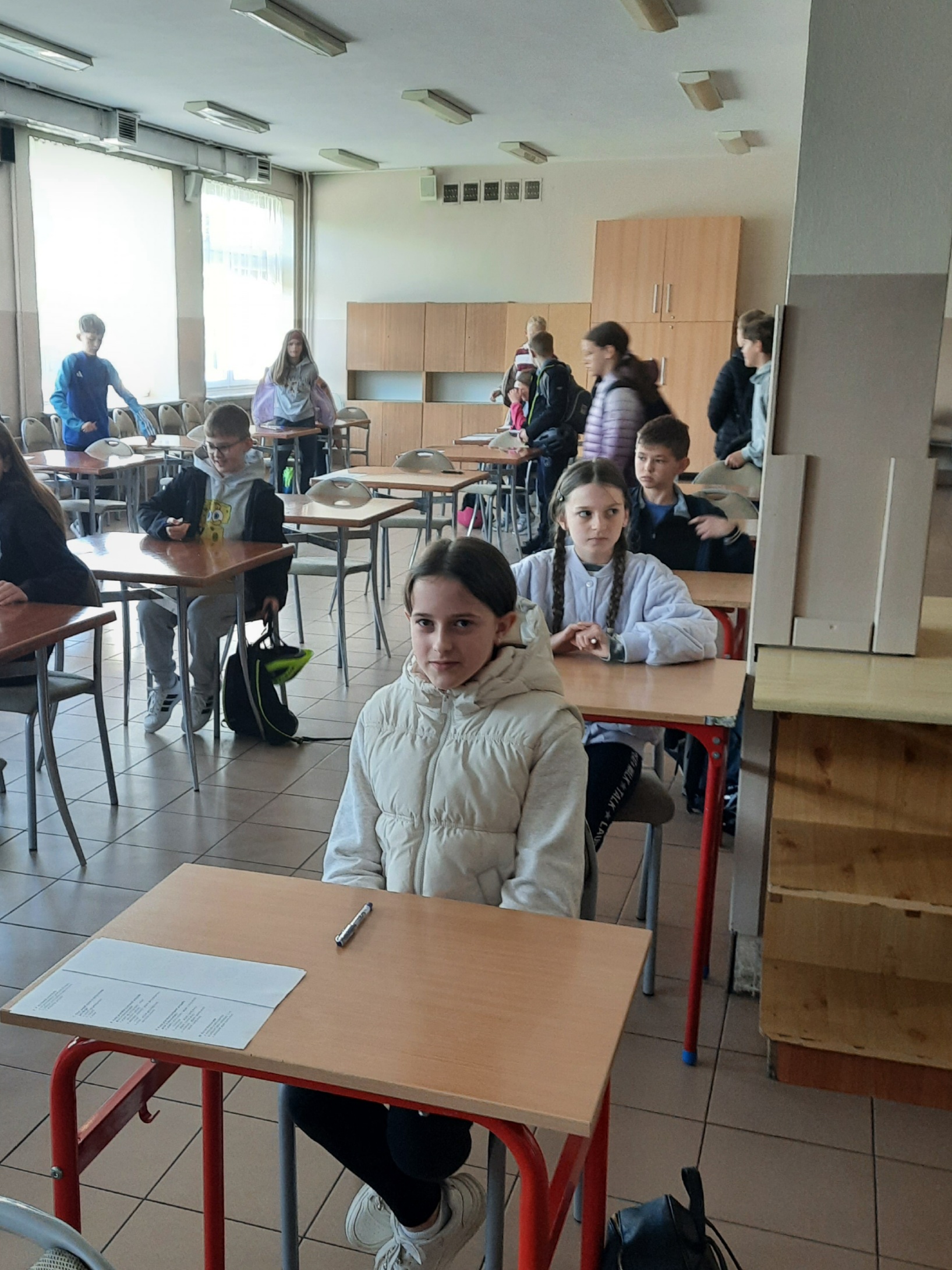 kilkoro uczniów siedzących w ławkach podczas konkursu
