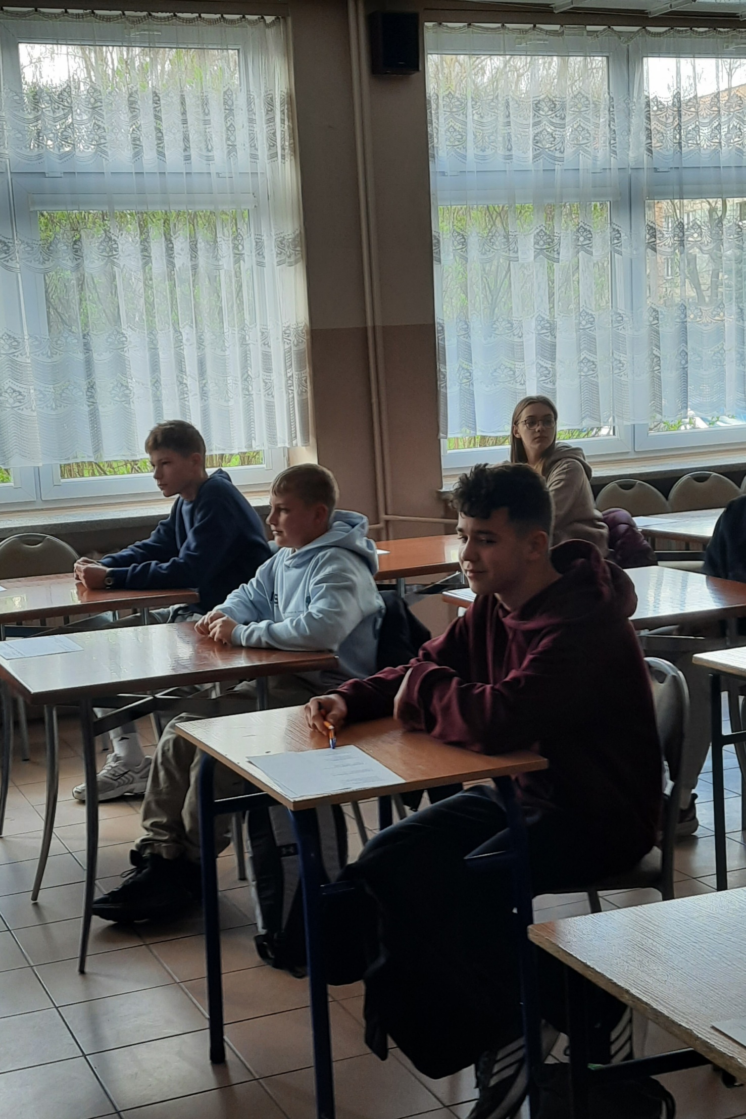 kilkoro uczniów siedzących w ławkach podczas konkursu