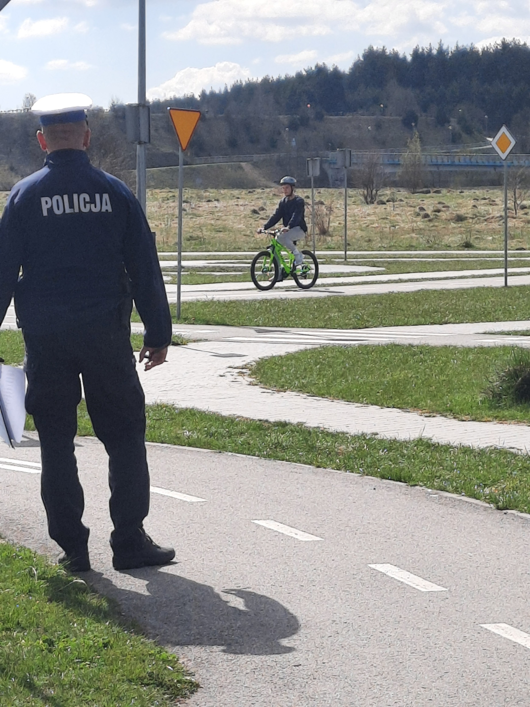 policjant, w tle uczeń jadący na rowerze