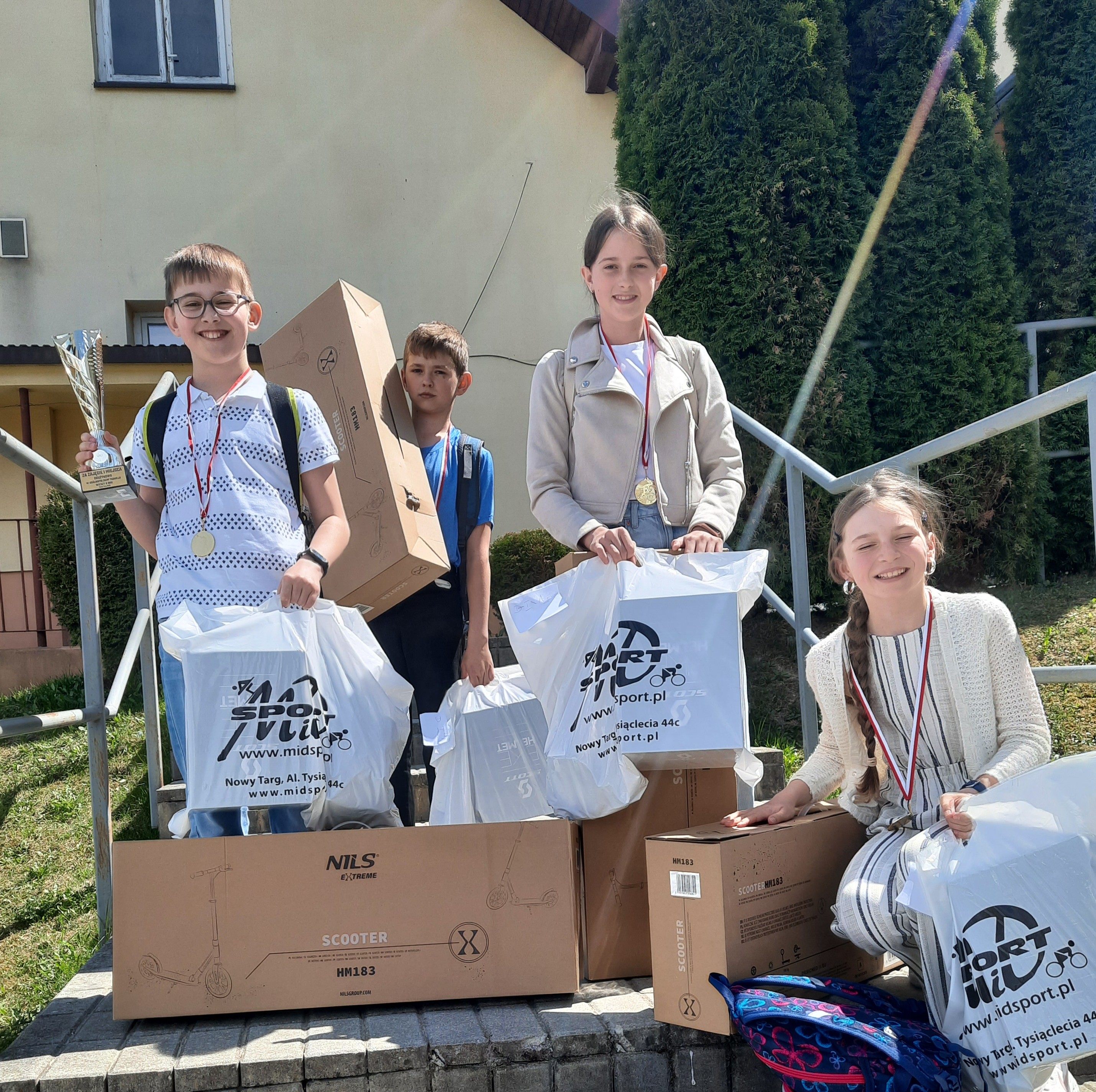 czworo uczniów z nagrodami na schodach