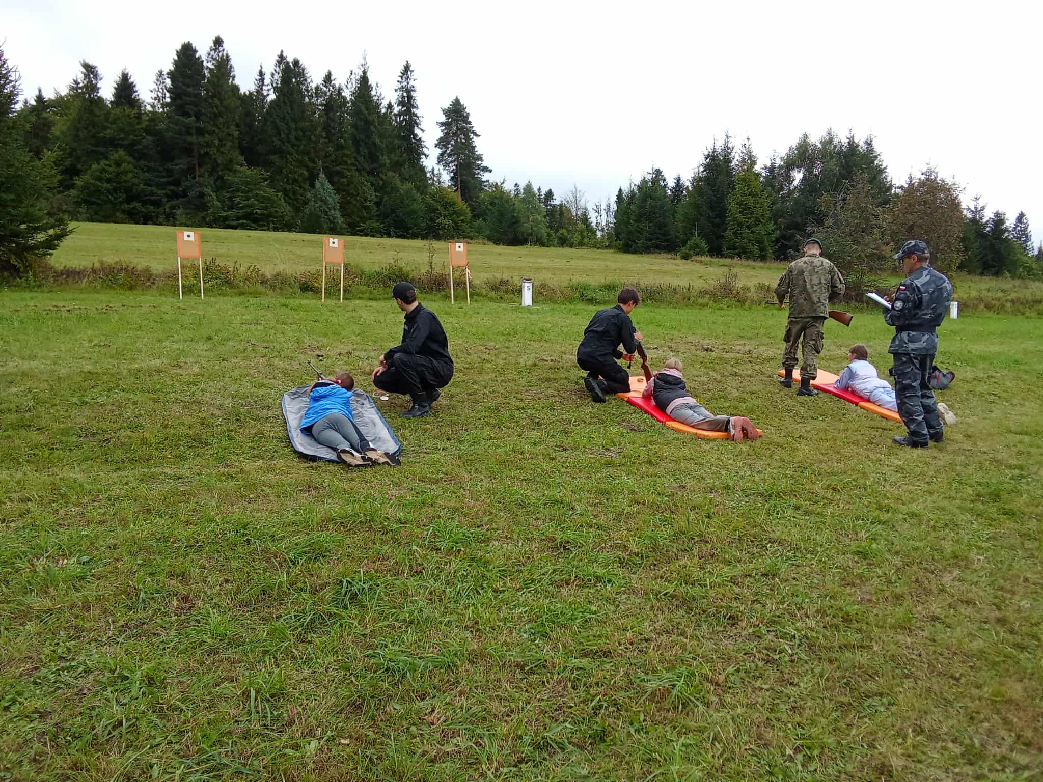 trzech uczniów z opiekunami podczas strzelania do celu