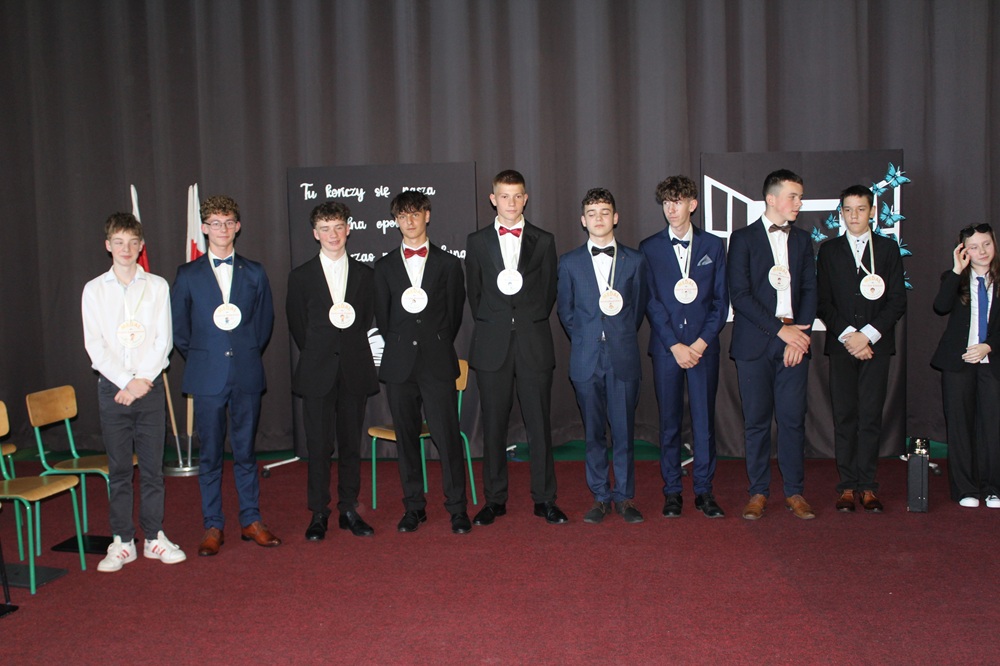 kilku chłopców absolwentów szkoły z pamiątkowymi medalami