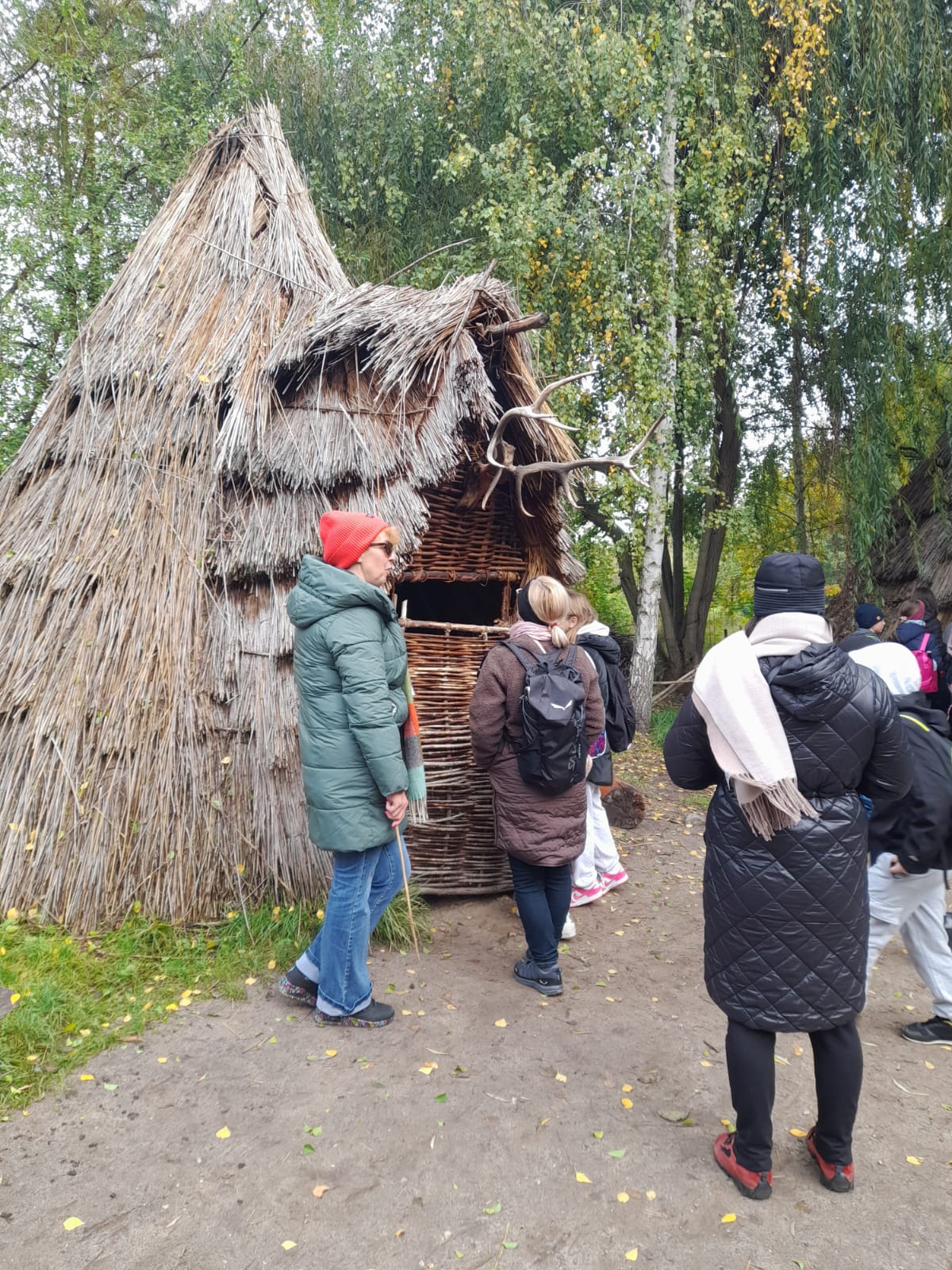 uczniowie zwiedzający szałas w Biskupinie