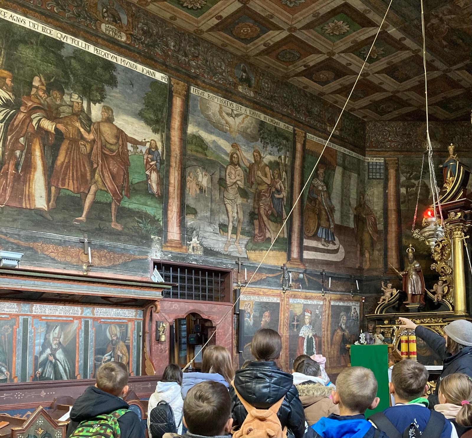 kilkoro uczniów zwiedzających kościół w Orawce